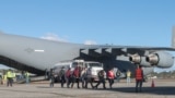 Гватемальцы сходят с американского военного самолета после депортации из США, 24 января 2025 года
